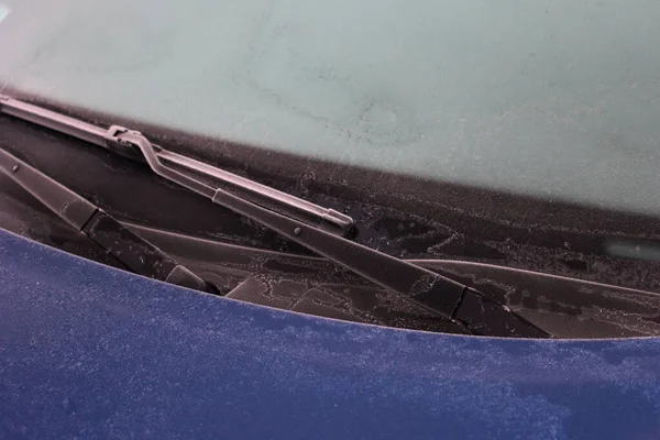 Mavi araba kış mevsiminde donla kaplı. Seçici odak noktasında arabanın ön görünümü.