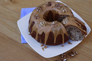 Dilimlenmiş ev yapımı tarçın ve ahşap bir tabakta karamel jöleli cevizli kek.