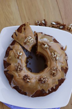 Dilimlenmiş ev yapımı tarçın ve ahşap bir tabakta karamel jöleli cevizli kek.