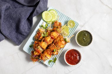 Paneer Satay, terbiye edilmiş paneer küpleriyle yapılan ve naneli turşuyla servis edilen ızgara bir Hint aperatifi.