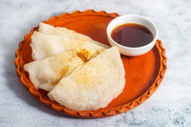 Geleneksel Bengali Chakuli pitha yumuşak mayalanmış, hafif kızarmış, hafif ekşi, ızgara ile pişirilmiş, jaggery, süt veya lezzetli refakatçilerle beslenen bir pirinç krebidir..