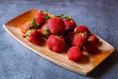 Parlak yüzeyi olan parlak kırmızı çilek, küçük tohumlar, tatlı aroma, sulu et ve taze yeşil yapraklar, tazeliği ve yazı simgeliyor..