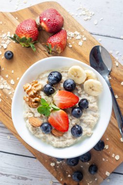 Çilek, muz, yabanmersini, fındık ve nane karışımı kremalı yulaf lapası.