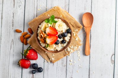 Çilek, muz, yabanmersini, fındık ve nane karışımı kremalı yulaf lapası.