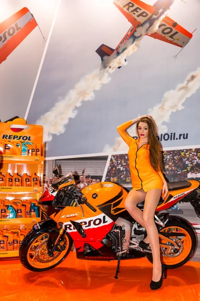 Motopark-2015 (BikePark-2015). Beautiful girl on sports bike near the stand with oils. — Stock Photo, Image