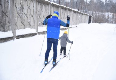 Baba ve çocuk kışın kar altında kayak yapıyorlar.