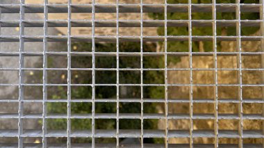 Yüksek yürüyüş yolunun metal ızgara zemininin ya da altında bitkiler ve taşlar olan köprünün makro fotoğrafını çek. Yüksek kalite fotoğraf