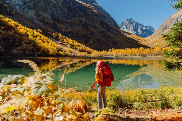 Hiker happy woman at lake in the autumnal mountains. Mountain lake and tourist