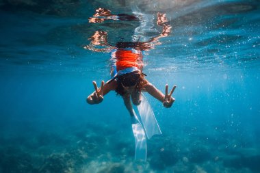 Özgür bir kadın, mavi denizde Noel şapkası takmış su altında poz veriyor. Noel tatili
