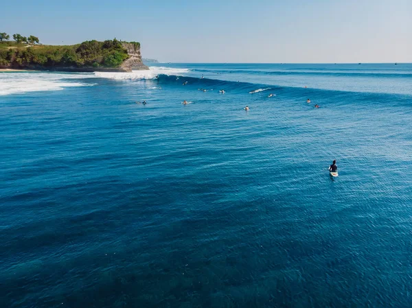 Aerial view of a surfers in blue ocean with waves. Top view