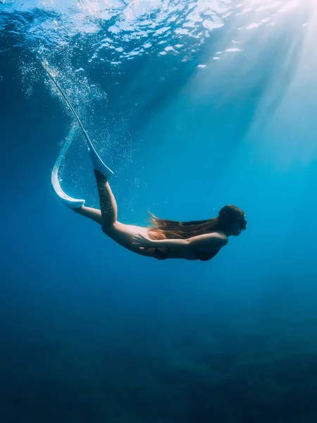 白いフィンを持つ自由な若い女性は 太陽光線で海底を滑空します 透明海でのフリーダイビング — ストック写真