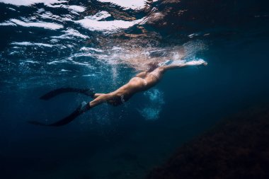 Mavi okyanusta yüzgeçleri olan yüzücü bir kadın..
