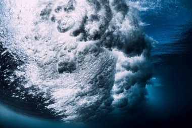 Suyun altında köpük ve kabarcıklarla dalga kırılıyor. Şeffaf okyanus suyu