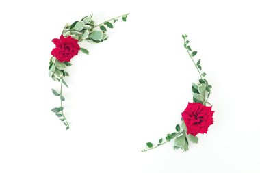 Kırmızı güllerden yapılmış yuvarlak çerçeve ve beyaz arka planda yapraklar. Düz yatış, Üst Görünüm