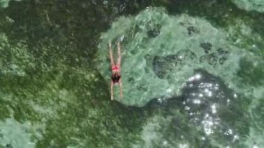 Turkuaz okyanus suyu ve yüzen kadın, hava manzaralı. Üst görünüm