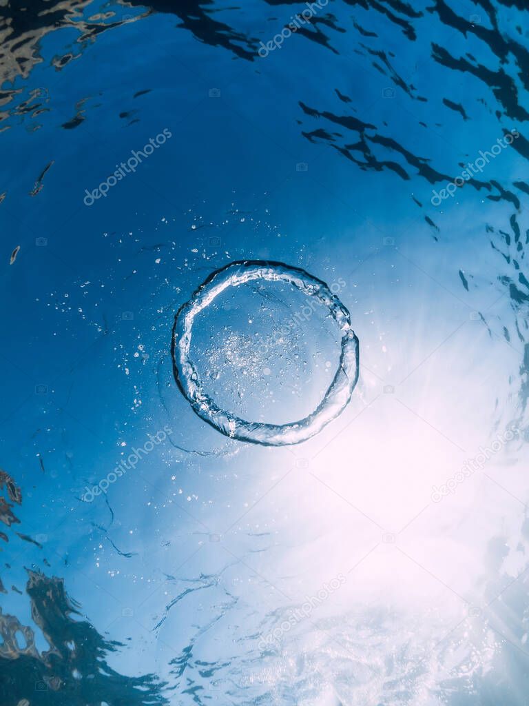 Ring bubble underwater and sun in blue ocean. Water texture.