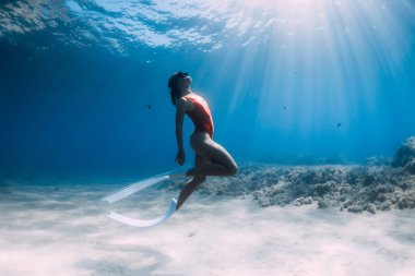 Beyaz yüzgeçli çekici bir kadın tropik denizde su altında poz veriyor..
