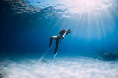 Beyaz yüzgeçli çekici bir kadın tropik denizde su altında poz veriyor..