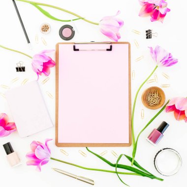 Pano, defter, kalem, pembe lale çiçekleri ve beyaz arka planda kozmetik ürünleri. Düz yatıyordu