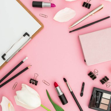 Pano, çiçekler, kozmetik ürünleri ve pembe üzerine izole edilmiş aksesuarlı bir blog yazarı kompozisyonu. Üst Manzara. Düz yatıyordu.