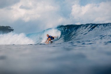 21 Ocak 2021. Bali, Endonezya. Kafkasyalı genç sörfçü sörf tahtasında okyanus dalgasına biniyor..