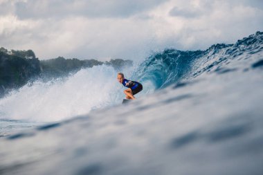 21 Ocak 2021. Bali, Endonezya. Kafkasyalı genç sörfçü sörf tahtasında okyanus dalgasına biniyor..