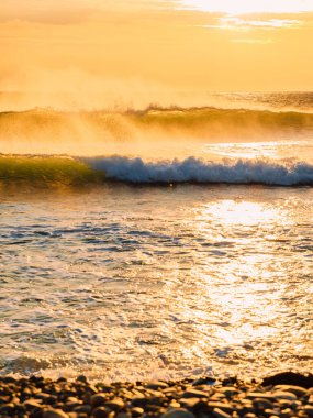 Sıcak gün batımında ya da gün doğumunda okyanus dalgaları. Dalgalar ve akşam ışığında esen güçlü rüzgar.