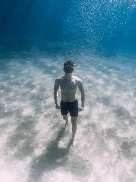 スポーツマンフリーダイバー滞在上の砂底水中で熱帯の海 — ストック写真