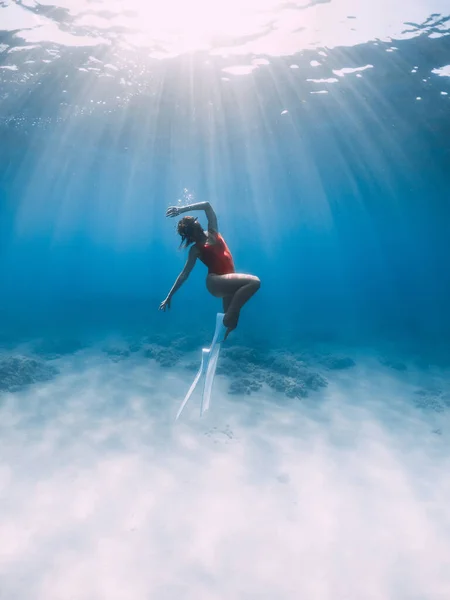 女性フリーダイバーで水着でフィンは 熱帯の海で砂の上に水中で滑空 — ストック写真