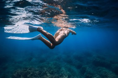 Yüzgeçleri serbest yüzgeçli çıplak kadın mavi okyanusta yüzüyor..