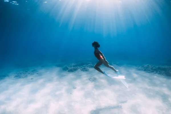 白いフィン付きの魅力的なフリーダイバーは 太陽光と青い海の中で水中で滑空し ポーズをとります スリム女の子ダイビング水中 — ストック写真