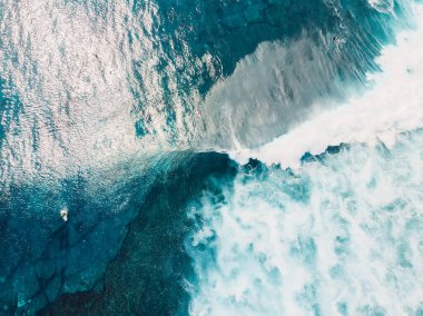 Bali adasındaki temiz okyanus suları, dalgalar ve sörfçülerin havadan görünüşü. Üst görünüm