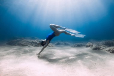 Yüzgeçleri olan bayan Freediver mavi okyanusta güneş ışığıyla poz veriyor ve süzülüyor..