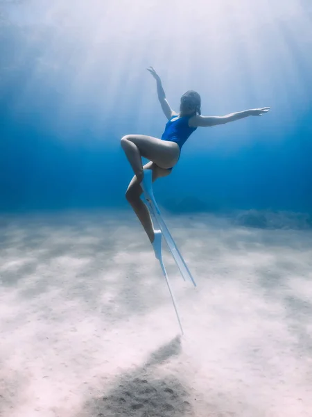 フィンを持つ女性のフリーダイバーは 太陽の光と海の中で水中でポーズやグライド 暖かい水の中でフリーダイビング — ストック写真