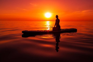 Sıska kız, gün batımında ya da gün doğumunda denize karşı kürek çekiyor. Kadınlar denizde yemek masasında rahatlar..