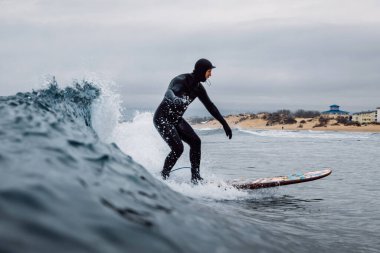 30 Nisan 2021. Anapa, Rusya. Dalgıç kıyafetli sörfçü varil dalgasında sörf tahtasında.