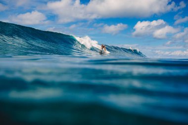 Nisan 04, 2021. Bali, Endonezya. Sörf yaparken tropikal okyanusta sportif genç bir kadın. Sörf tahtasında sörf yapan kız ve mükemmel okyanus dalgası. 