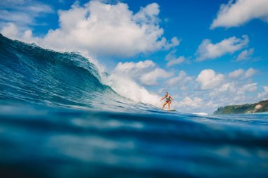 Nisan 04, 2021. Bali, Endonezya. Sörf yaparken tropikal okyanusta sportif genç bir kadın. Sörf tahtasında sörf yapan kız ve mükemmel okyanus dalgası. 