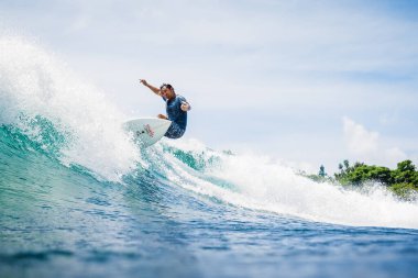 20 Ağustos 2021. Bali, Endonezya. Mavi dalgada sörf tahtasında sörfçü. Tropikal okyanusta sörf yapmak