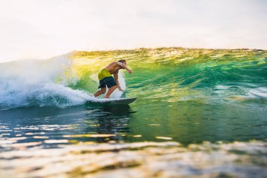 20 Ağustos 2021. Bali, Endonezya. Gün batımında sörf tahtasında sörfçü. Tropikal okyanusta sörf yapmak