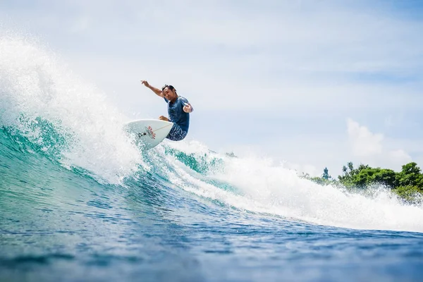 20 Ağustos 2021. Bali, Endonezya. Mavi dalgada sörf tahtasında sörfçü. Tropikal okyanusta sörf yapmak