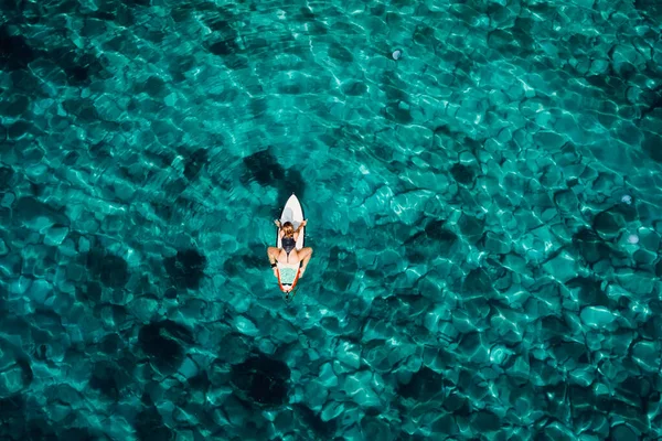 冲浪女孩坐在透明的蓝绿色海洋的冲浪板上 与冲浪女子的空中视野 — 图库照片