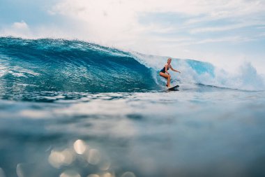 Tropikal okyanusta sörf tahtasında sörf yapan kız. Sörf yaparken sportif kadın.