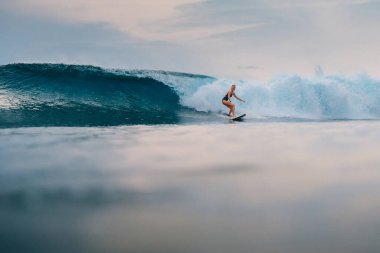 Sörf tahtasındaki sörfçü kız ve mükemmel fıçı dalgası. Bali 'de sörf yaparken sportif bir kadın..
