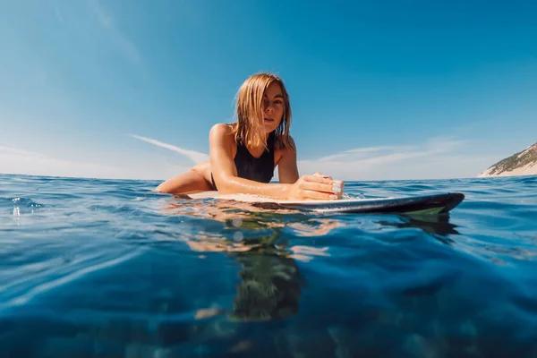 魅力的なブロンドサーフ女の子座っていますでサーフボードで青い海 — ストック写真