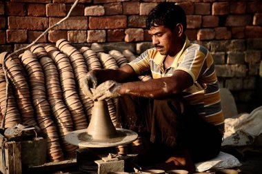 Varanasi / Hindistan - 04 Mart 2013: Hintli adam ellerini kullanarak kilden bir tepsi yapıp fabrikada kilden bir kase yapıyor..