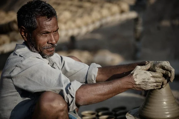 印度瓦拉纳西 2013年3月4日 一位面带微笑的印度年轻人手握粘土坐在转盘上 在工厂里做一碗粘土 — 图库照片