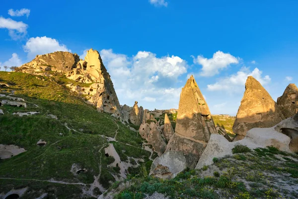 Uchisar Kalesi ve kasaba kum taşı dağları tünel ve pencerelerle doludur. Sabah, güneş Türkiye 'nin Kapadokya kentinin altın tepelerine ve mavi gökyüzüne vuruyor.