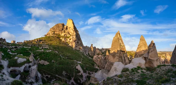 Panorama uchisar kalesi ve kasaba, tüneller ve pencerelerle dolu kumtaşından dağlardır. Sabah, güneş Türkiye 'nin Kapadokya kentinin altın tepelerine ve mavi gökyüzüne vuruyor.