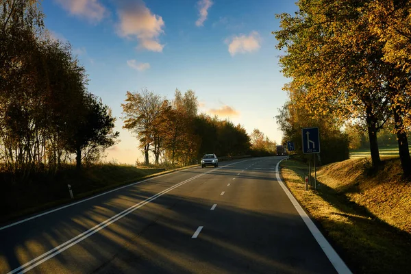 Travel with beautiful European driving routes, highways and cars and both sides with big trees changing color in autumn, rural views and evening lights create a romantic atmosphere.